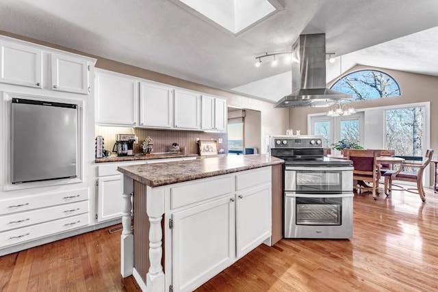 kitchen with light wood-style floors, double oven range, island exhaust hood, and white cabinets