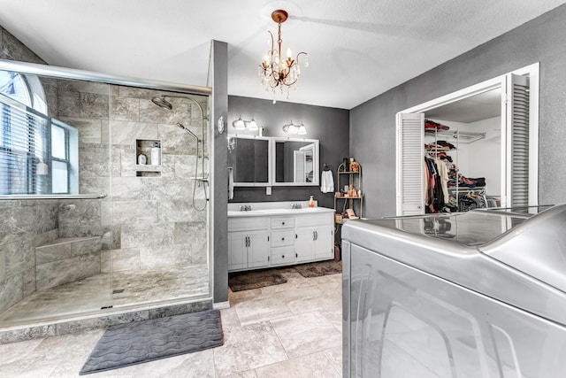 full bathroom featuring a stall shower, a chandelier, a textured ceiling, and vanity