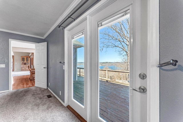 doorway to outside featuring carpet floors, visible vents, a textured wall, ornamental molding, and baseboards