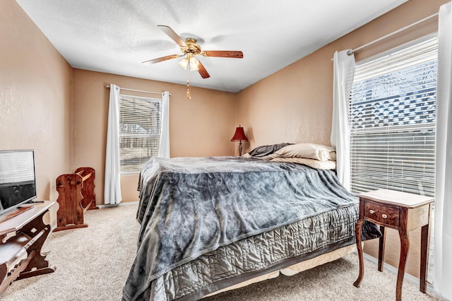 carpeted bedroom featuring ceiling fan, multiple windows, and a textured ceiling