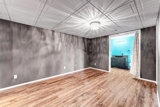 unfurnished room with an ornate ceiling, a sink, baseboards, and wood finished floors