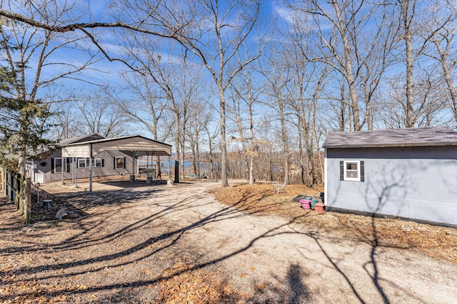 view of yard with a detached carport and dirt driveway