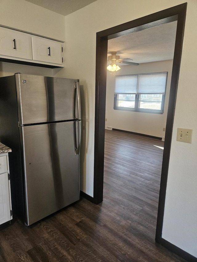 kitchen with ceiling fan, dark wood-type flooring, stainless steel fridge, and white cabinets