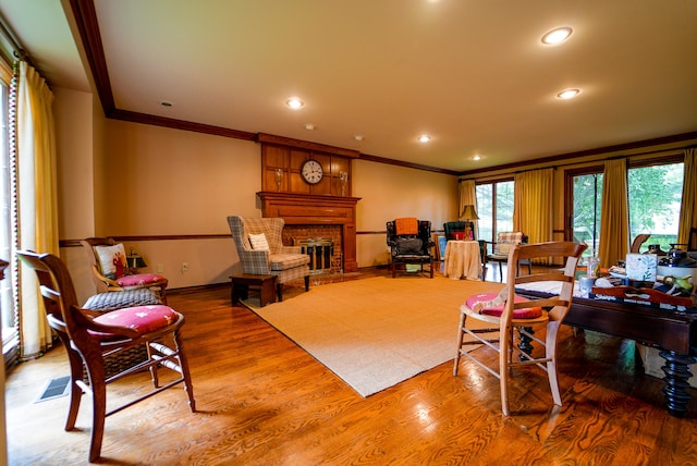 living room with hardwood / wood-style flooring, crown molding, and a large fireplace