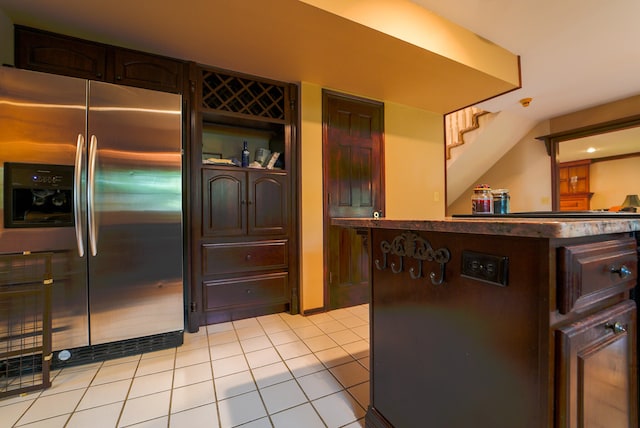 kitchen featuring light tile patterned flooring, dark brown cabinetry, and stainless steel fridge