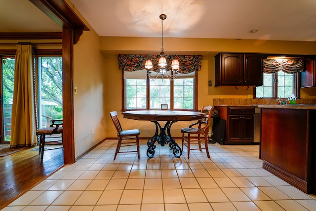 dining space with a notable chandelier, light wood-type flooring, and a healthy amount of sunlight