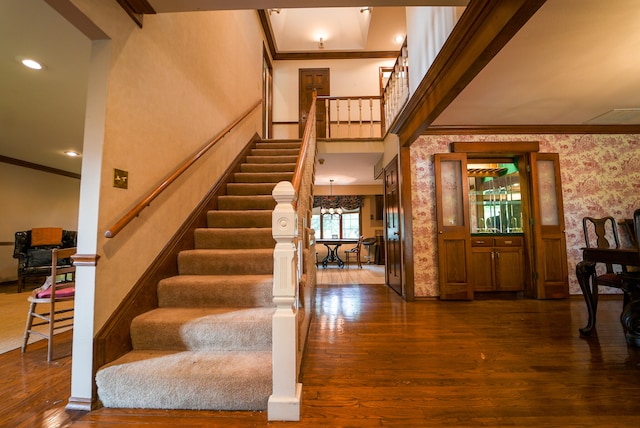 entryway featuring wood-type flooring, crown molding, and a chandelier