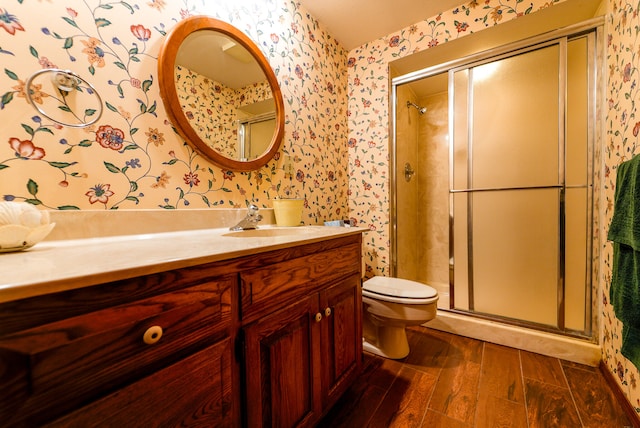 bathroom with wood-type flooring, vanity, toilet, and an enclosed shower