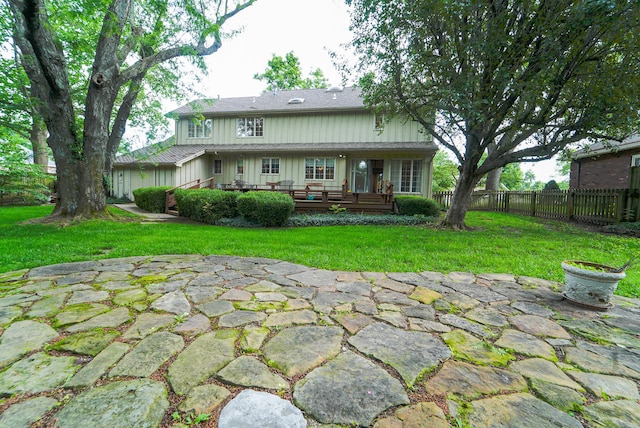 rear view of property with a wooden deck, a yard, a patio, and an outdoor fire pit