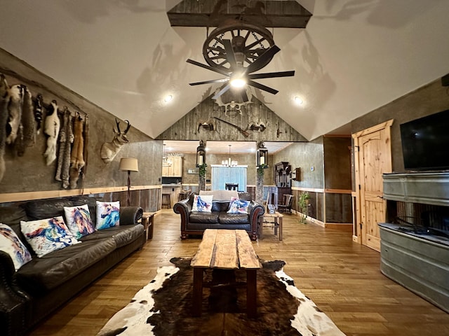 living room featuring ceiling fan with notable chandelier, vaulted ceiling, and hardwood / wood-style flooring