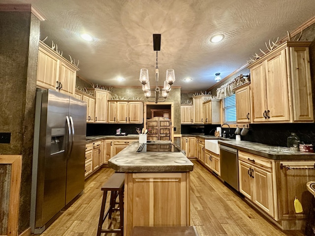 kitchen with stainless steel appliances, hanging light fixtures, light wood-type flooring, and a center island