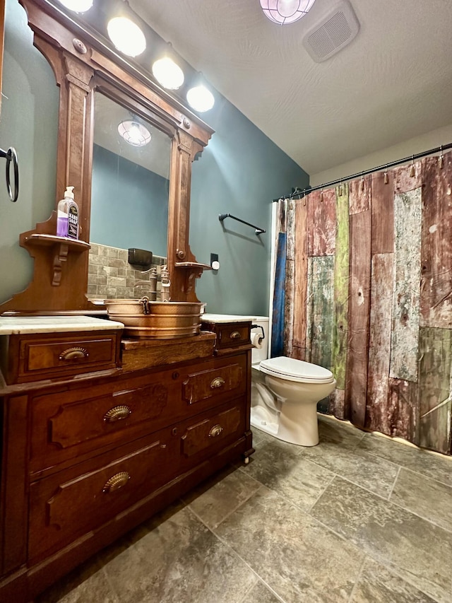 bathroom featuring a textured ceiling, vanity, and toilet