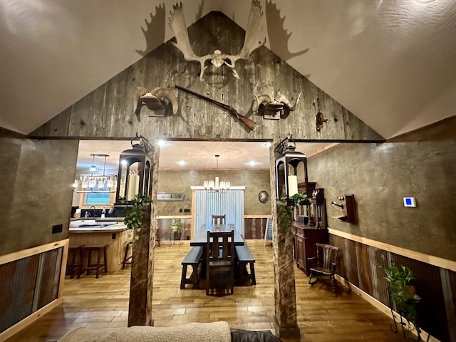 dining space with an inviting chandelier, hardwood / wood-style flooring, and wooden walls