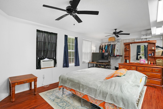 bedroom with cooling unit, ceiling fan, a closet, and wood-type flooring