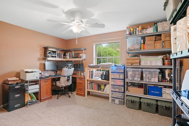 home office featuring light carpet, ceiling fan, and a textured ceiling