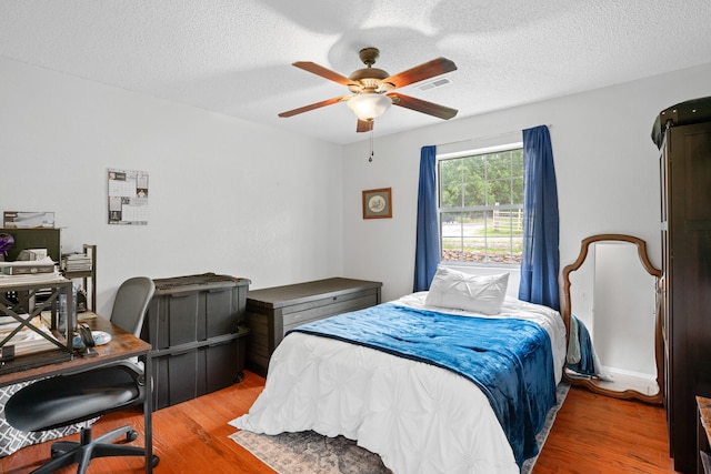 bedroom featuring ceiling fan, a textured ceiling, and wood-type flooring