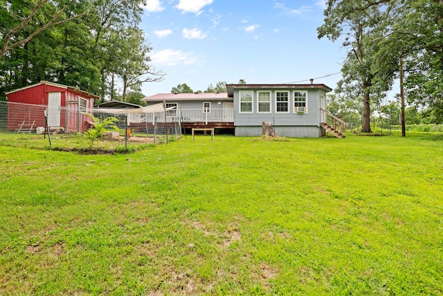 rear view of house with a yard, an outbuilding, and a deck