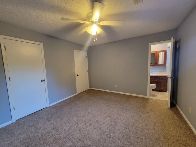 unfurnished bedroom featuring ceiling fan, connected bathroom, a textured ceiling, a closet, and light carpet