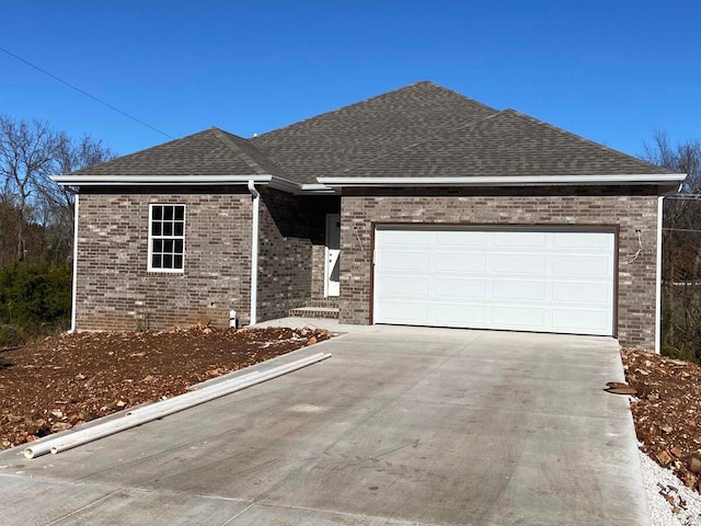 single story home with a garage, roof with shingles, brick siding, and driveway