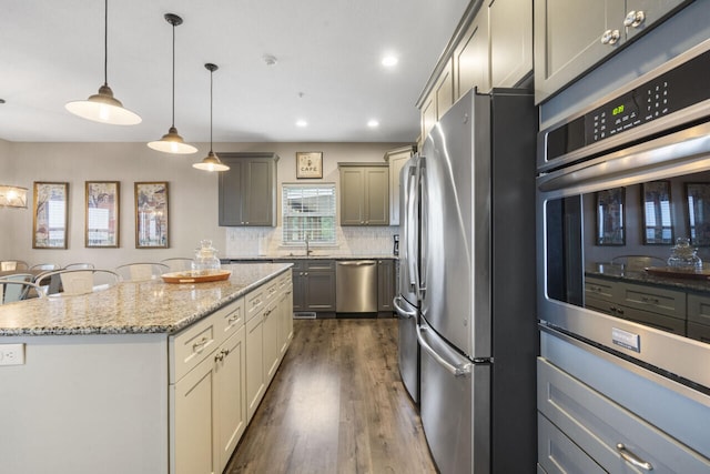 kitchen with hanging light fixtures, gray cabinets, appliances with stainless steel finishes, a center island, and dark hardwood / wood-style flooring