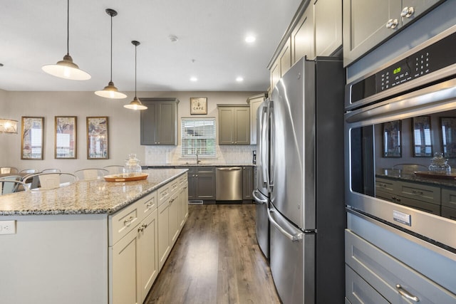 270 Chateau Cove Dr, Branson, MO 65616 - kitchen with dark wood-style floors, light stone counters, stainless steel appliances, a sink, and a kitchen island
