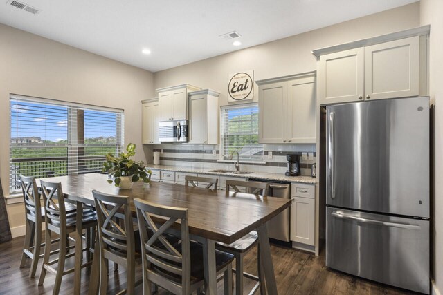 kitchen featuring light stone counters, decorative backsplash, dark wood-type flooring, sink, and appliances with stainless steel finishes