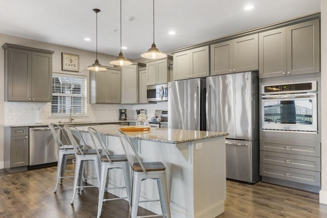 kitchen featuring pendant lighting, appliances with stainless steel finishes, dark hardwood / wood-style flooring, and a center island