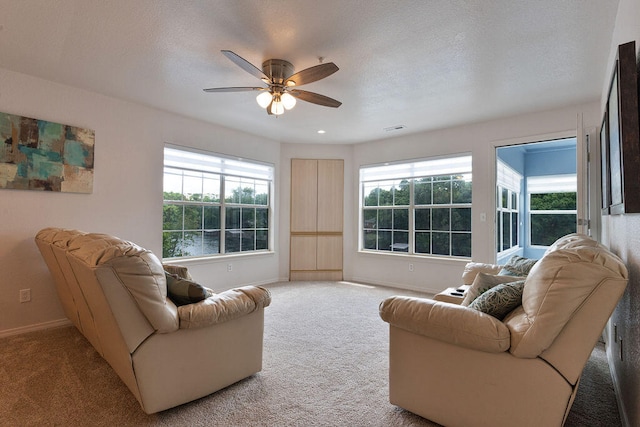 carpeted living room with ceiling fan and a textured ceiling