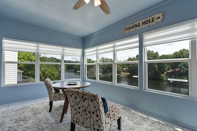 sunroom / solarium with ceiling fan, plenty of natural light, and a water view