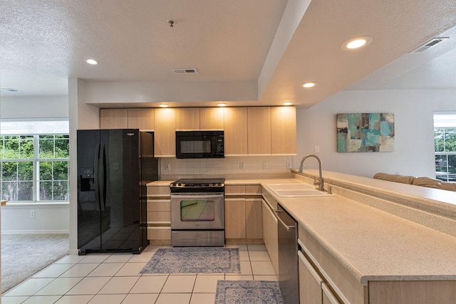 kitchen with light brown cabinetry, sink, backsplash, black appliances, and light tile patterned floors