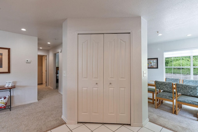 corridor featuring light colored carpet and a textured ceiling