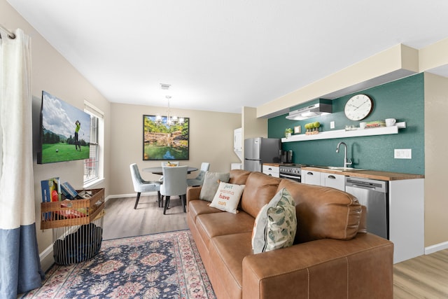 living room featuring light hardwood / wood-style floors, a chandelier, and sink