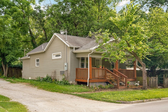 view of front of home with driveway, a shingled roof, and fence