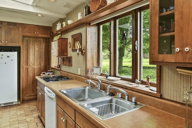kitchen featuring white appliances, a wealth of natural light, brown cabinets, and a sink