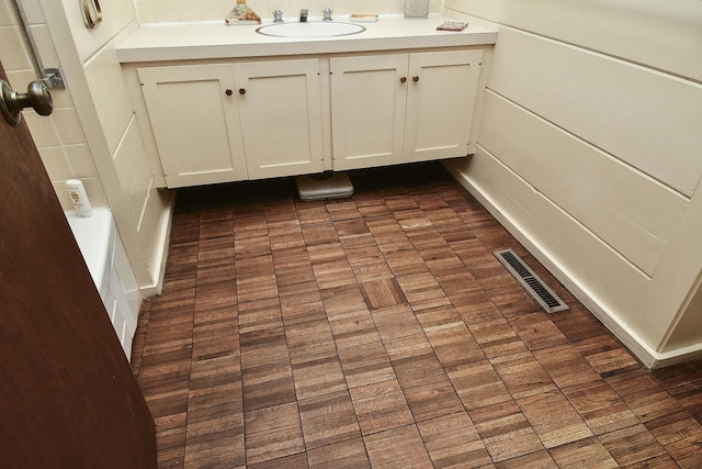 full bath featuring brick patterned floor, vanity, and visible vents