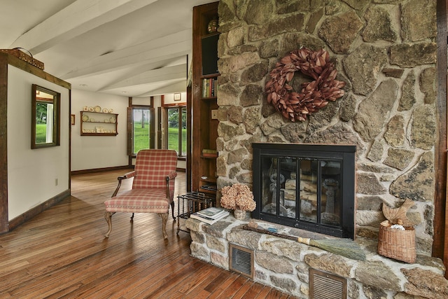 living area featuring hardwood / wood-style flooring, baseboards, visible vents, and a fireplace