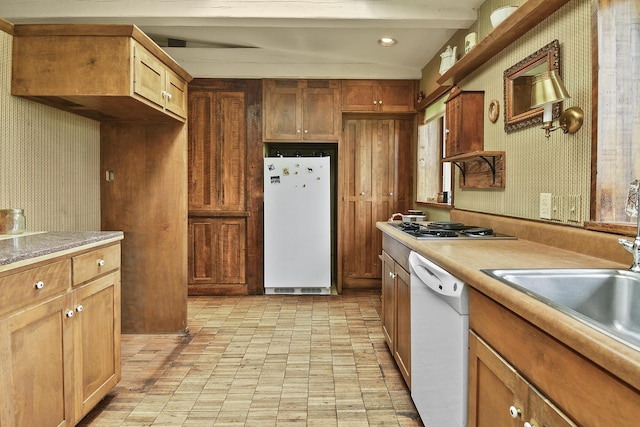 kitchen with a sink, fridge, wallpapered walls, white dishwasher, and stainless steel cooktop