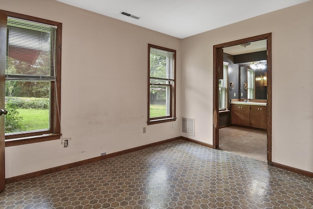 empty room featuring baseboards, visible vents, and a sink