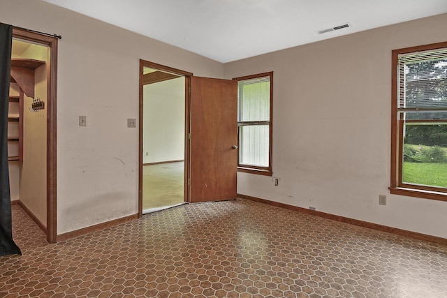 unfurnished room with baseboards, visible vents, and a healthy amount of sunlight