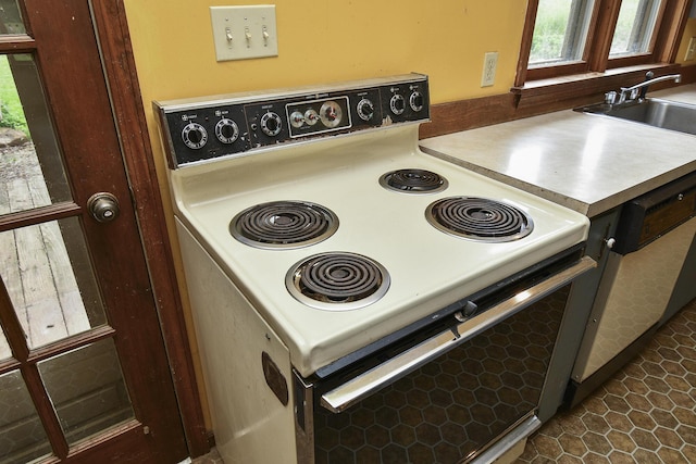 kitchen with dark tile patterned floors, white electric range, a healthy amount of sunlight, and a sink