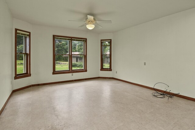 empty room featuring light floors, ceiling fan, and baseboards