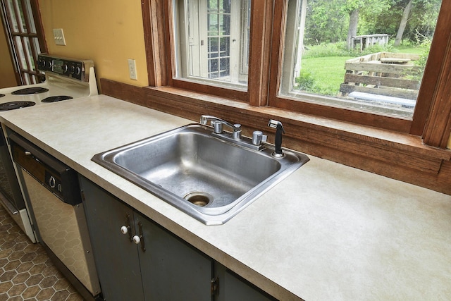kitchen with range with electric stovetop, a sink, light countertops, and a wealth of natural light