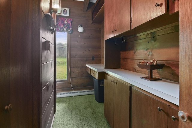 kitchen with a baseboard radiator, carpet floors, wooden walls, and light countertops