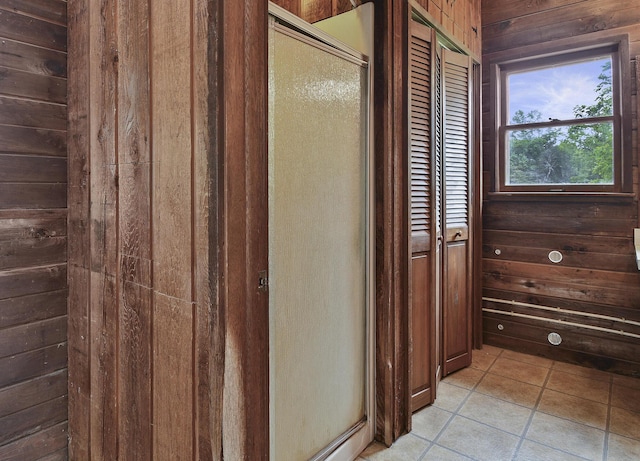 bathroom with tile patterned floors, wooden walls, and a stall shower