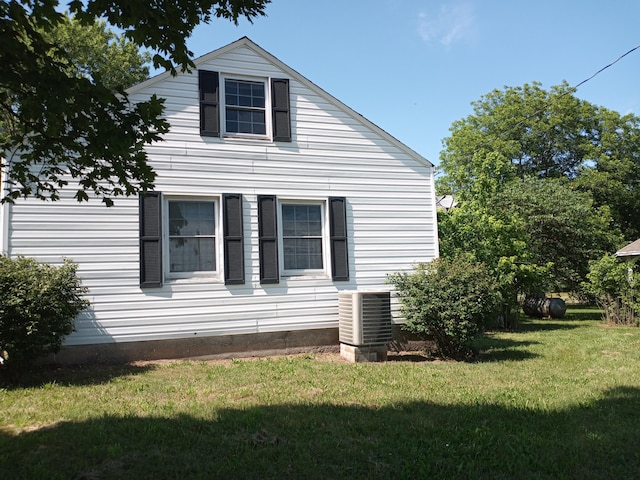 view of property exterior with a lawn and central air condition unit