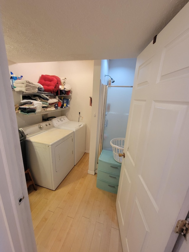 washroom featuring a textured ceiling, independent washer and dryer, and light hardwood / wood-style flooring