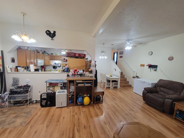 5317 E Ave, Morrisville, MO 65710 - living area featuring light wood-style flooring, stairs, and ceiling fan with notable chandelier