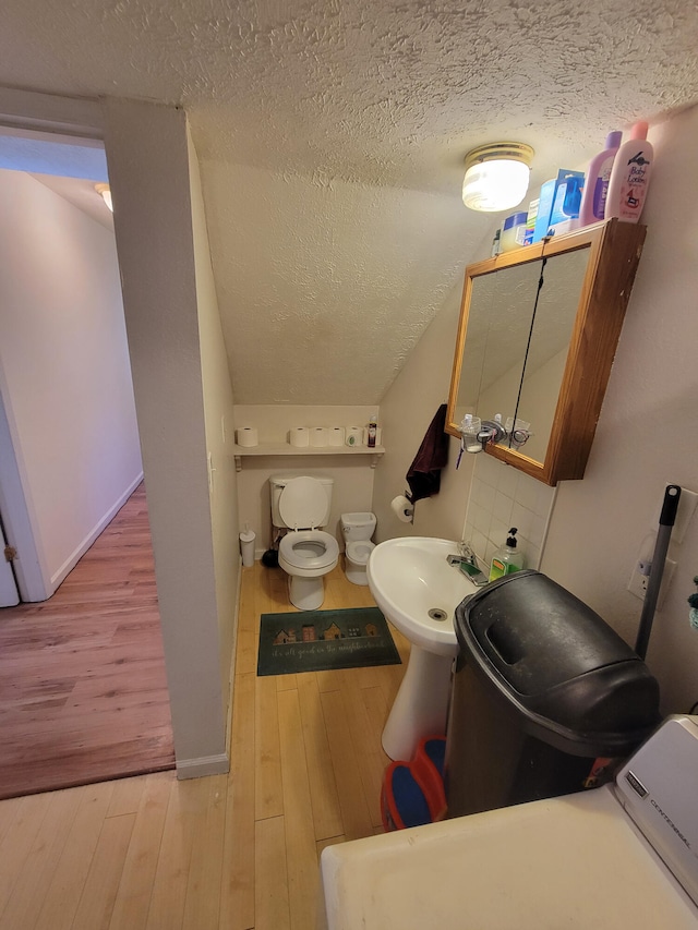 bathroom with hardwood / wood-style flooring, washer / dryer, and a textured ceiling