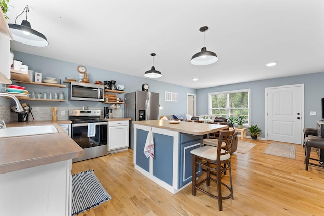 kitchen featuring light hardwood / wood-style floors, a breakfast bar, sink, appliances with stainless steel finishes, and white cabinetry