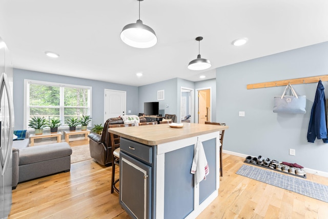 kitchen featuring light wood-type flooring, pendant lighting, a breakfast bar area, and a center island